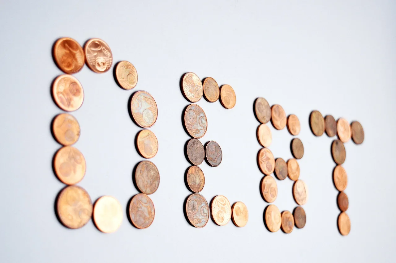 The word debt spelled with coins for the post How to Get Out of Debt by Budget Plan Pro