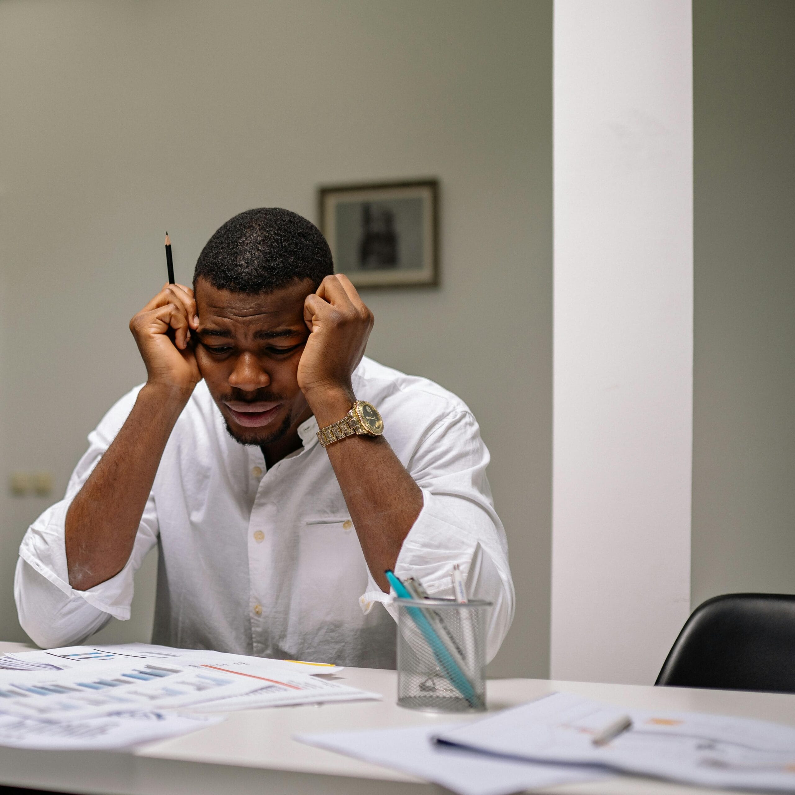 A worried businessman in corporate attire handling stress at his workspace, possibly due to budgeting mistakes beginners make.